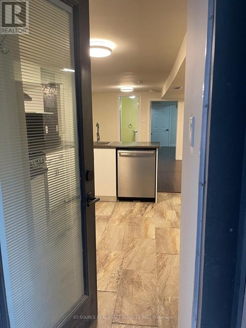 A kitchen with a stainless steel refrigerator and a wooden floor.