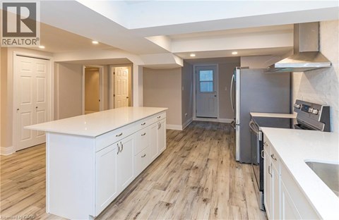 A modern kitchen with white cabinets and a wooden floor.