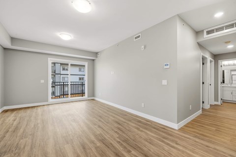 A spacious room with wooden flooring and a balcony with a railing.