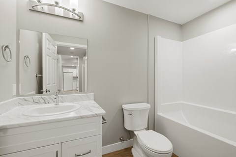 A white bathroom with a toilet, sink, and bathtub.