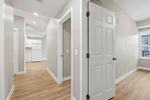 A white door is in a room with wood floors and white walls.