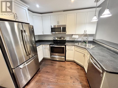 A kitchen with a stainless steel refrigerator and white cabinets.