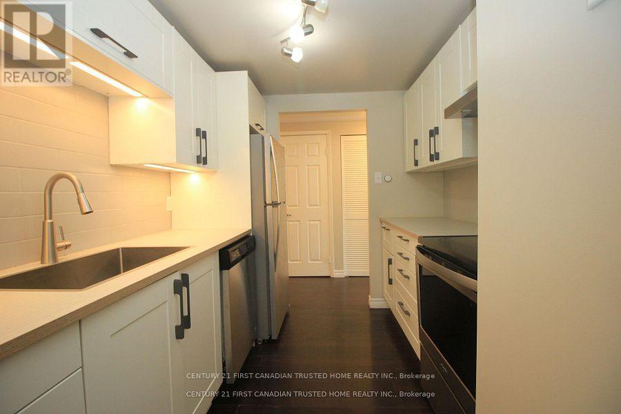 A kitchen with white cabinets and a black fridge.