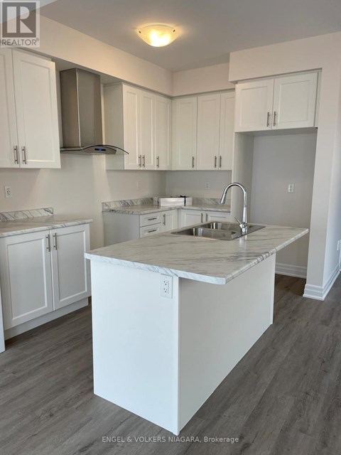 A kitchen with white cabinets and a marble island.