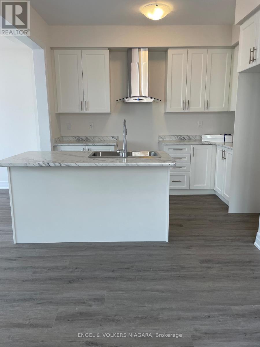 A kitchen with white cabinets and a marble countertop.