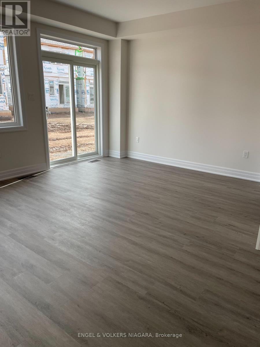 A room with a grey floor and white walls, with a view of a construction site through the window.