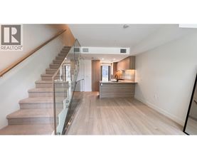 A spacious living room with a staircase leading to the upper floor.