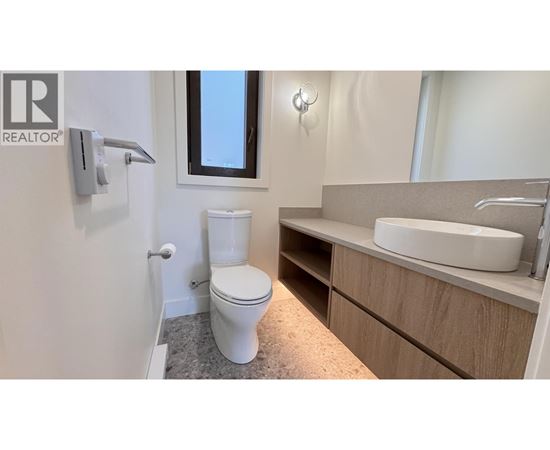 A bathroom with a toilet, sink, and mirror.