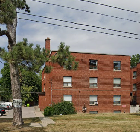A red brick building with a tree in front of it.