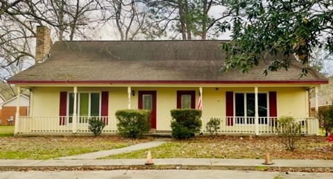 A yellow house with a red door and a flag on the front porch.