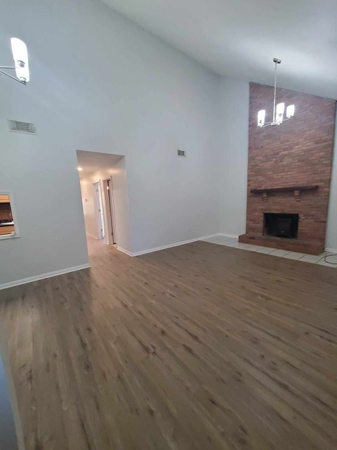 A room with wooden floors and a brick fireplace.