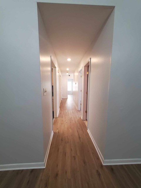 A long hallway with wood floors and white walls.