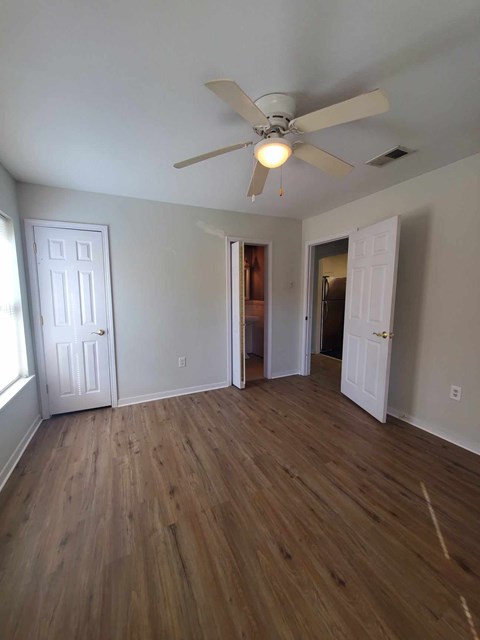 A room with a ceiling fan and wooden floors.