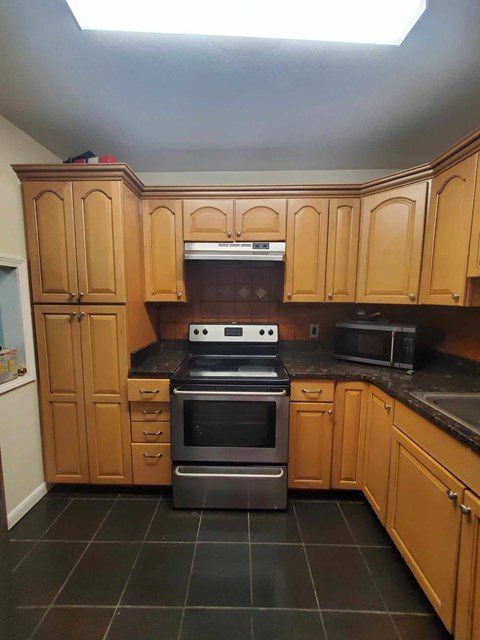 A kitchen with wooden cabinets and a black stove top.