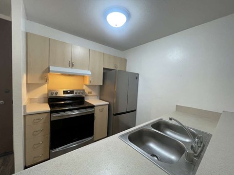 A kitchen with a sink, stove, and cabinets.