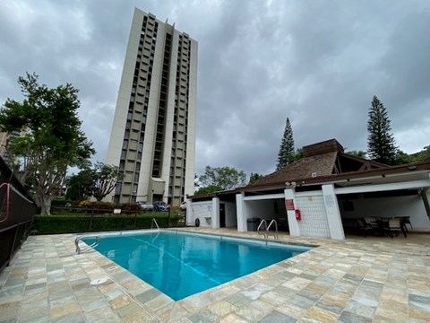 A swimming pool in a backyard with a tall building in the background.