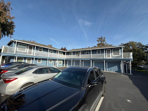 A car is parked in front of a blue building.