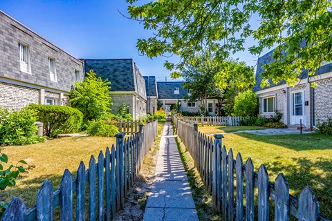 A sunny day in a quiet neighborhood with a wooden fence and houses on both sides.