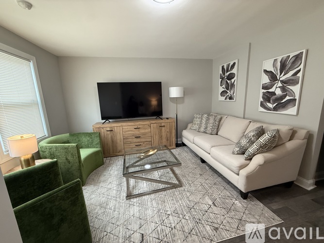A living room with a white couch, a green chair, and a television.