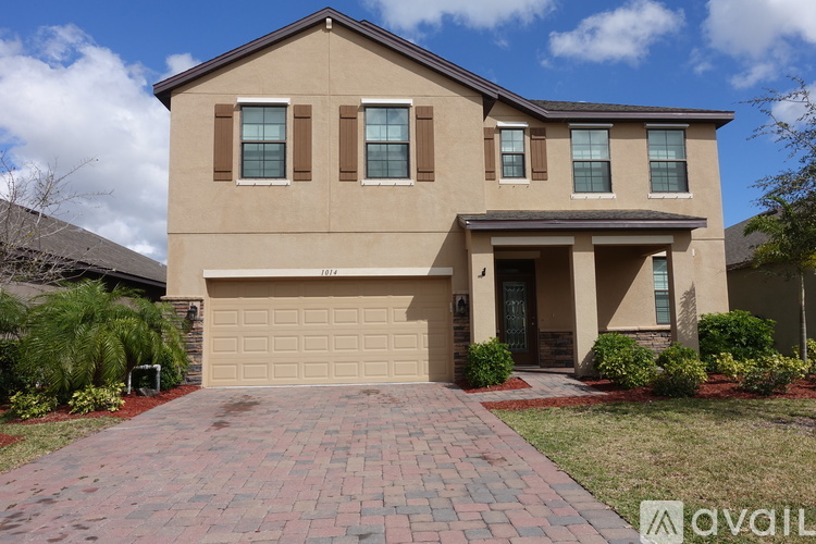A beige house with a brick pathway leading to a garage.