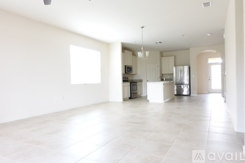 A spacious kitchen with white cabinets and appliances, a dining area with a table and chairs, and a large window letting in natural light.