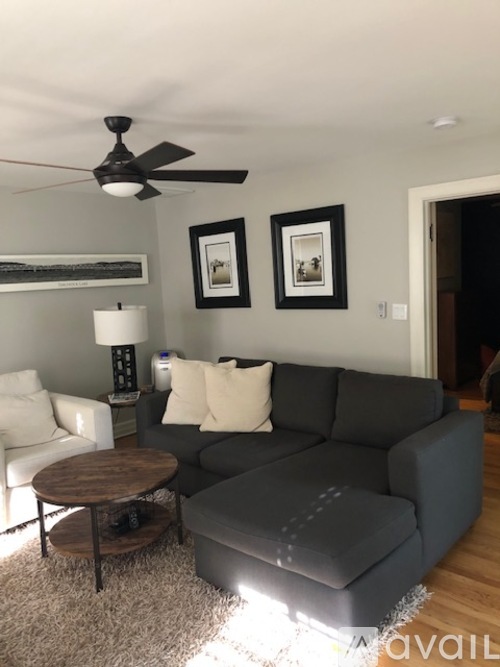 A living room with a grey couch, a white chair, and a wooden coffee table.