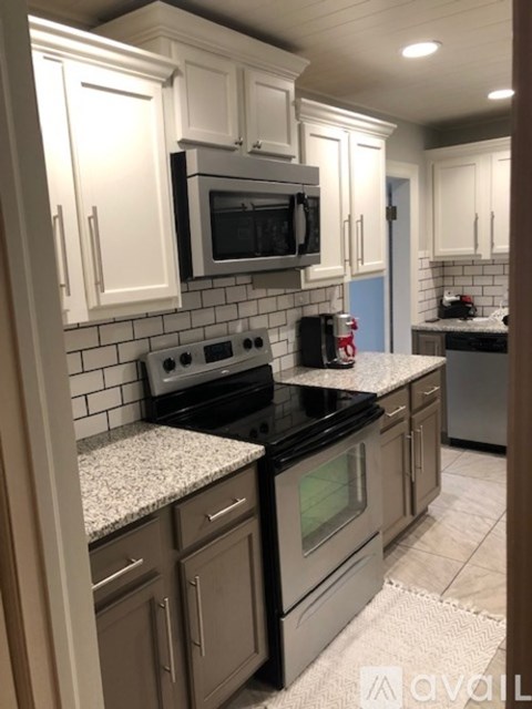 A kitchen with a black stove top oven and a black microwave above it.