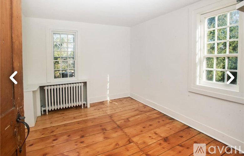 A room with wooden floors and a window with a view of trees.