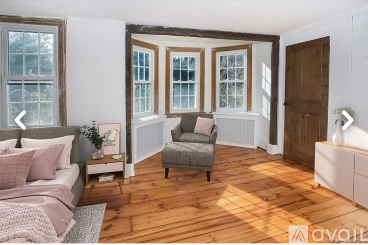 A bedroom with a bed, chair, and window.