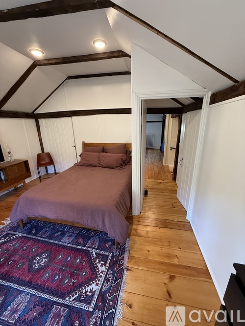 A bedroom with a bed and a rug on the floor.