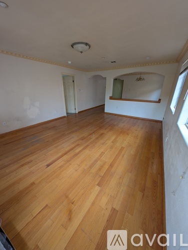 A room with wooden flooring and a window on the right side.