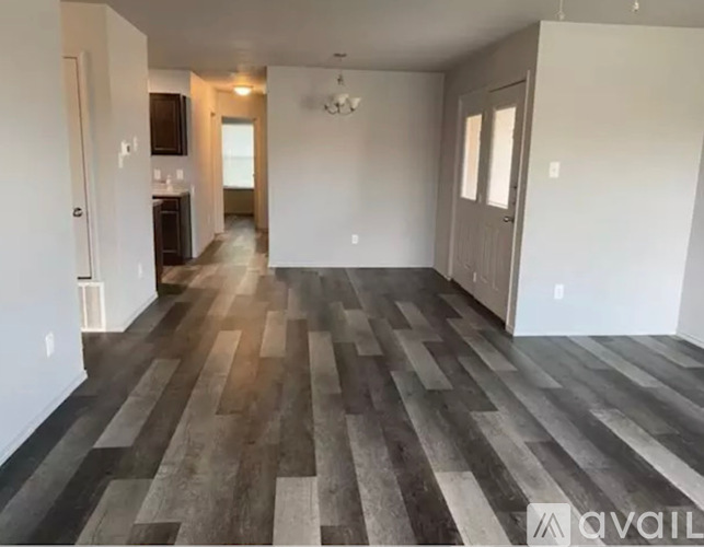 A spacious room with wooden flooring and white walls.