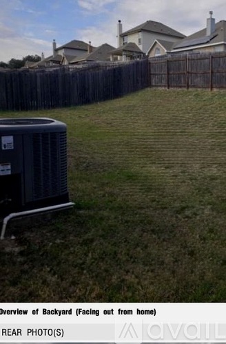 A backyard with a fence and a grassy area.