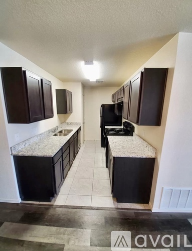 A kitchen with black cabinets and a granite countertop.