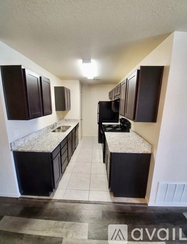 A kitchen with black cabinets and a granite countertop.