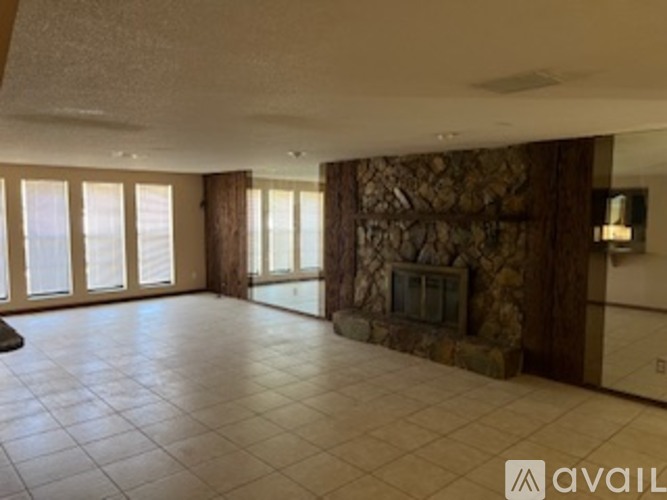 A living room with a stone fireplace and a flat screen TV.