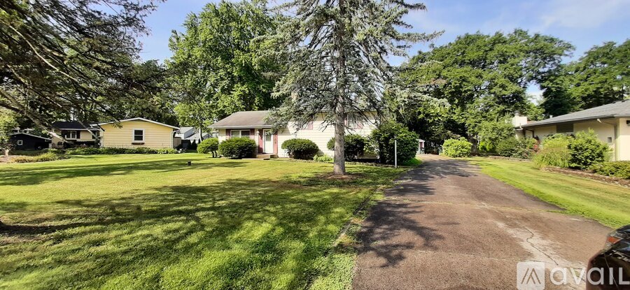 A tree-lined driveway leads to a house with a lawn on either side.