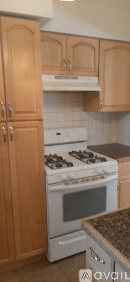A kitchen with wooden cabinets and a white stove.