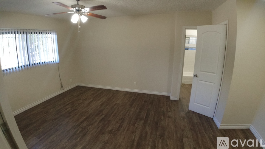 A room with a ceiling fan and wooden flooring.