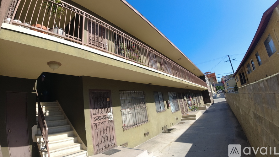 A street view of a building with a balcony and a door with a metal grill.