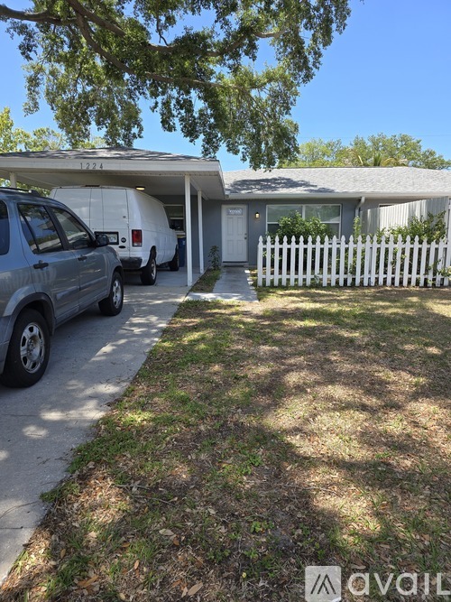 A white picket fence and a garage with a car in front.