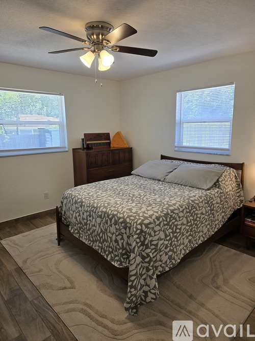 A bedroom with a bed, dresser, and ceiling fan.