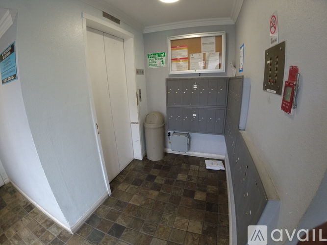 A room with a white door and a red phone on the wall.