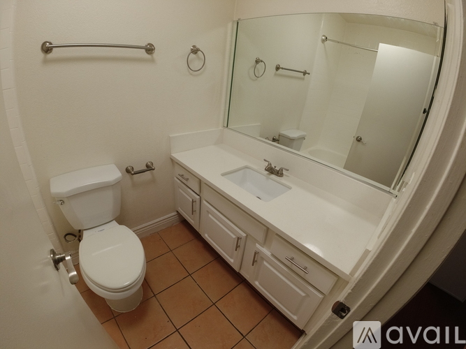A bathroom with a toilet, sink, and mirror.