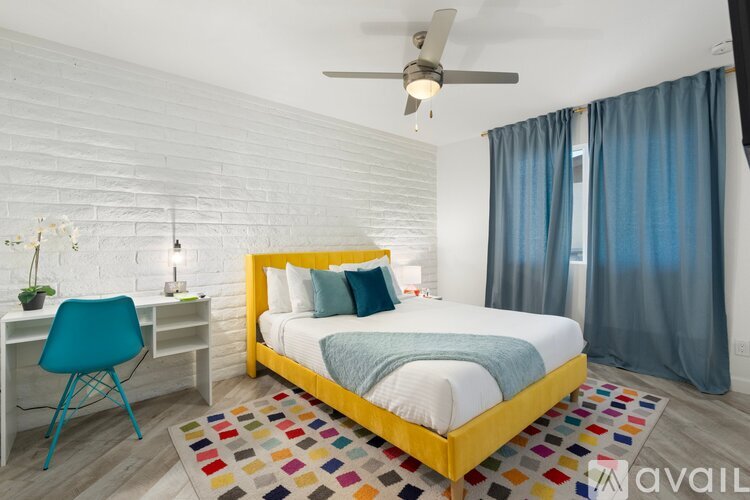 A bedroom with a white brick wall, a yellow bed, and a blue chair.
