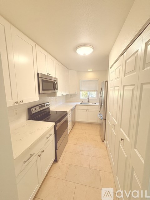 A kitchen with white cabinets and appliances.