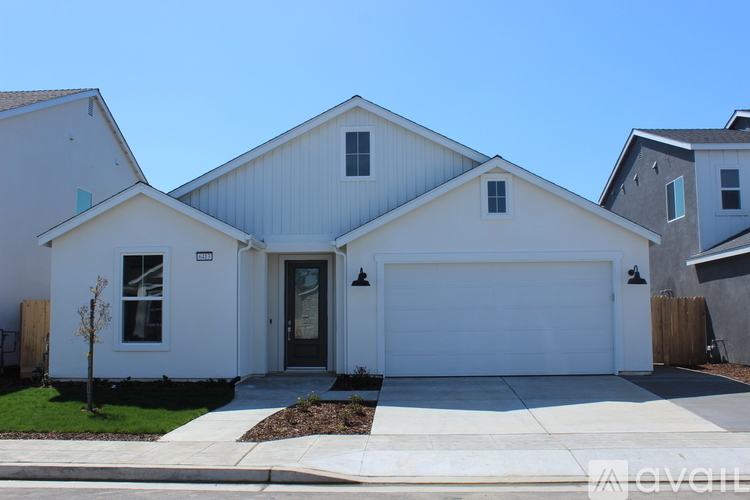 A white house with a grey roof and a black garage door.