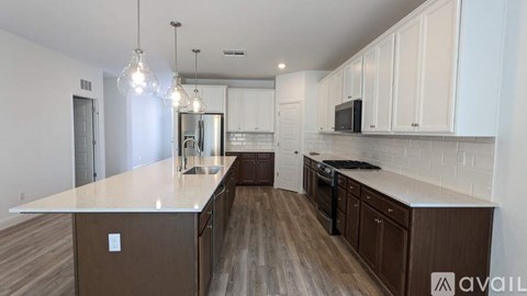 A kitchen with white cabinets and a brown island.