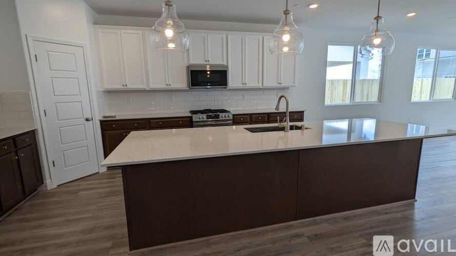 A kitchen with white cabinets and a brown island.
