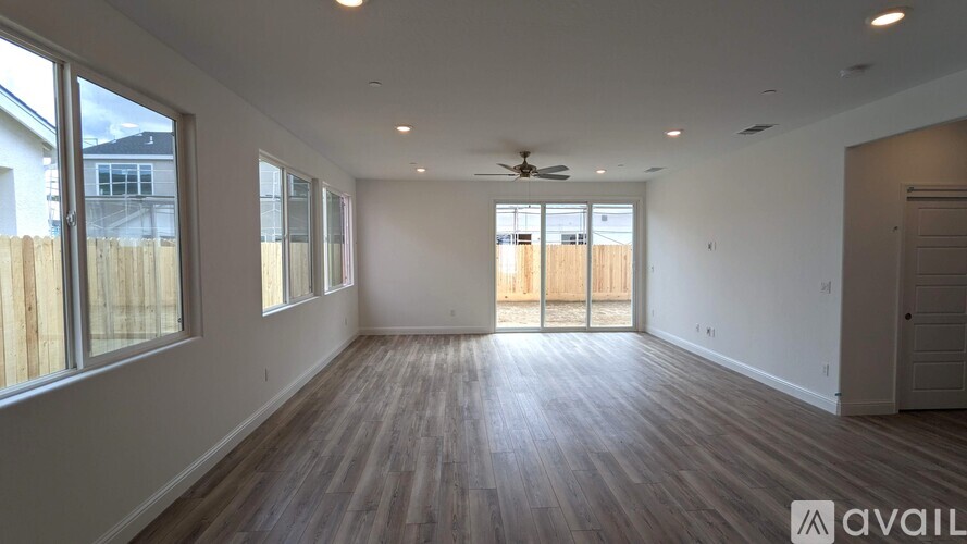 A spacious room with wooden flooring and a ceiling fan.
